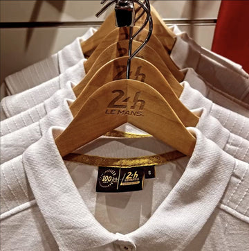 Cintres en bois naturel avec le logo 24h Le Mans gravé, sur des polos blancs